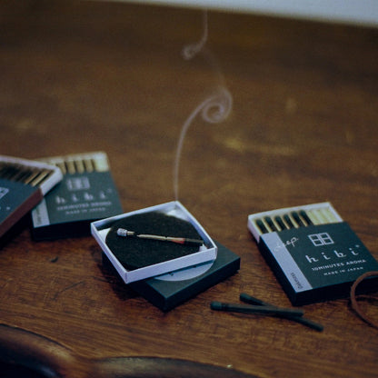 hibi Oak Moss Incense Match lit on wooden table