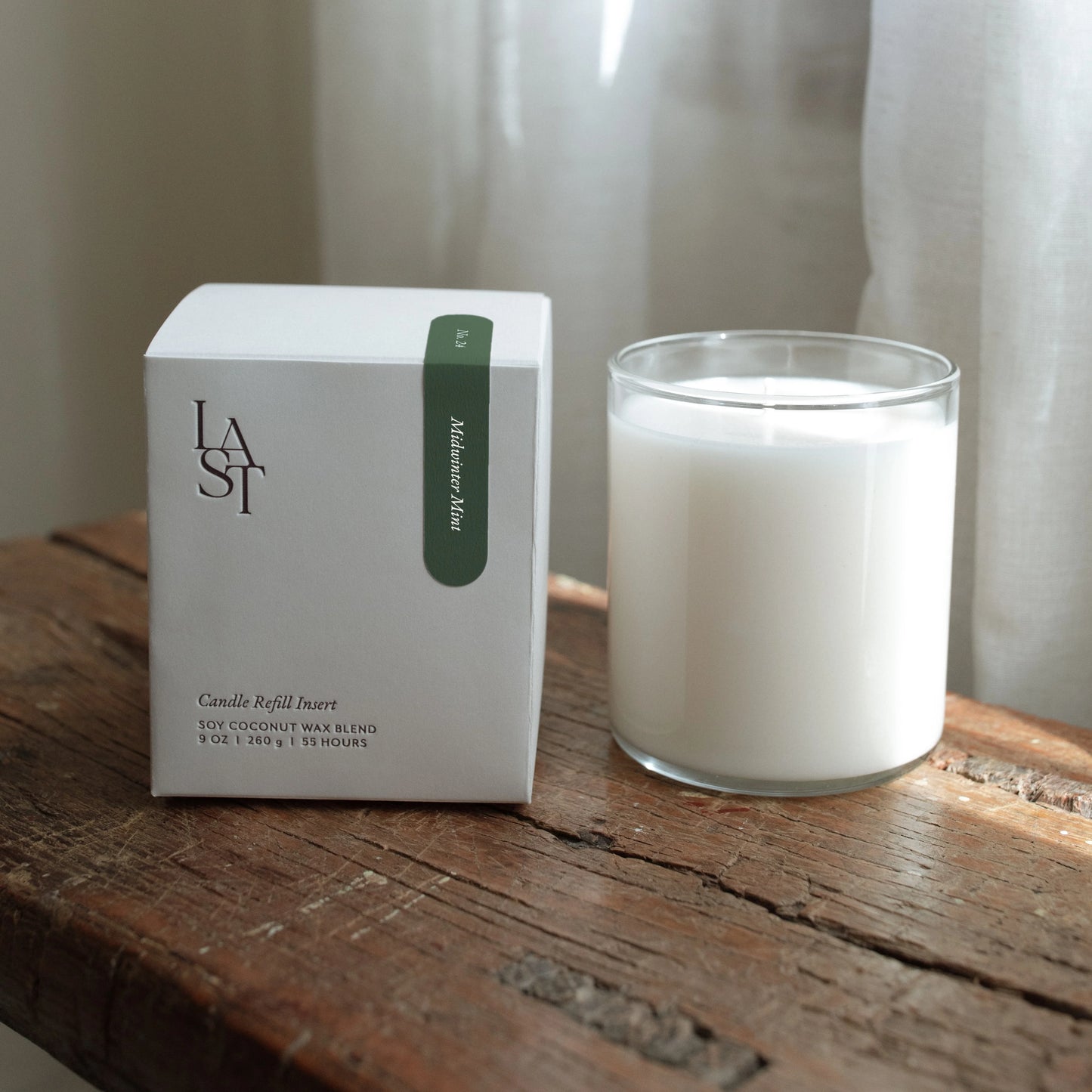 Candle and packaging on a wooden surface with a neutral background