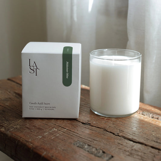 Candle and packaging on a wooden surface with a neutral background