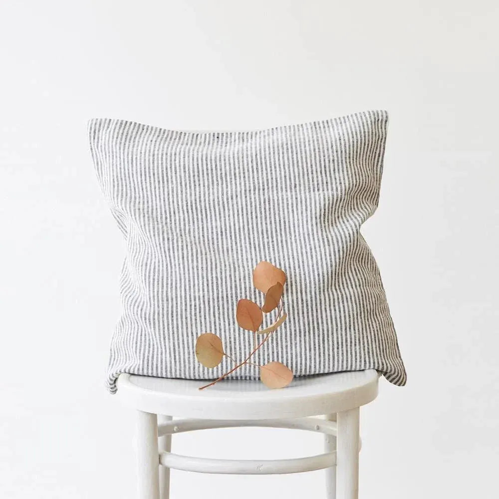 Striped pillow on a white stool against a light gray background