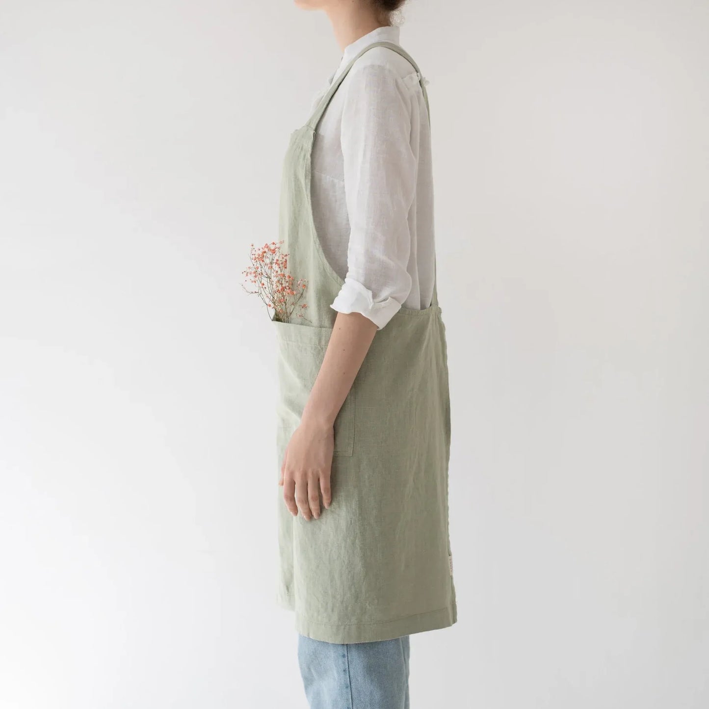 Linen crossback apron in sage colour, side profile