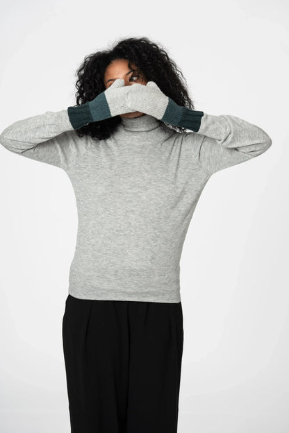 Person wearing a gray sweater and black pants with gloves on a white background