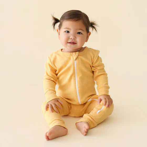 Baby wearing a yellow outfit on a beige background