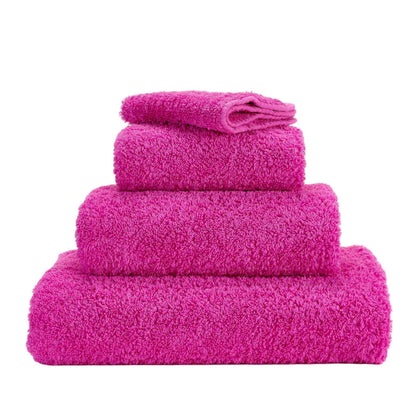 Set of four pink towels stacked on a white background