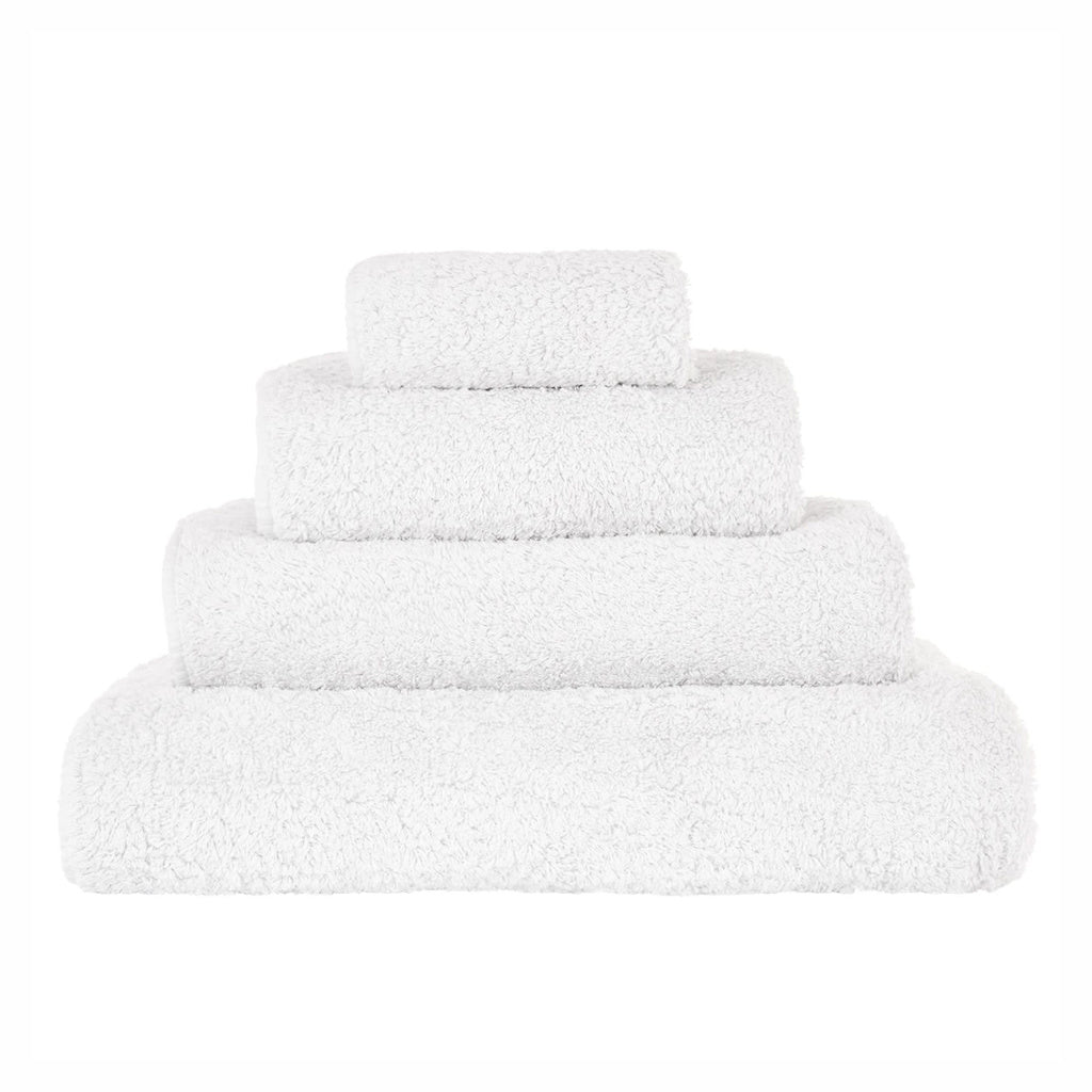 A stack of white Abyss towels in various sizes, displaying the plush texture of the cotton.