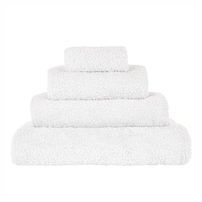 A stack of white Abyss towels in various sizes, displaying the plush texture of the cotton.