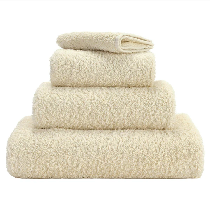 A set of ecru colored Abyss towels displayed neatly stacked on top of each other.