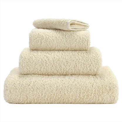 A set of ecru colored Abyss towels displayed neatly stacked on top of each other.