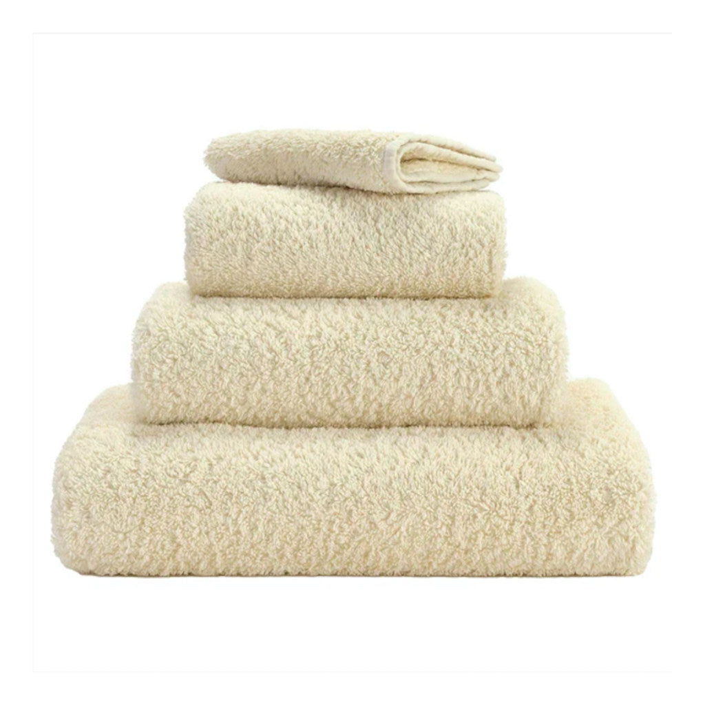 A set of ecru colored Abyss towels displayed neatly stacked on top of each other.