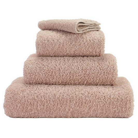 A set of light pink/brown towels neatly stacked on top of each other, showing a plush, soft texture.