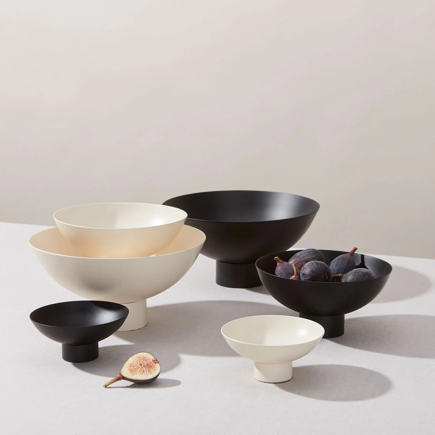 Set of powder-coated stainless steel bowls in various sizes on a light surface with a neutral background