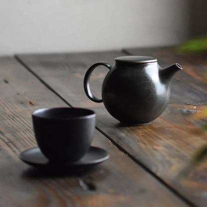 KINTO PEBBLE Teapot in Black, 500ml next to tea cup and saucer