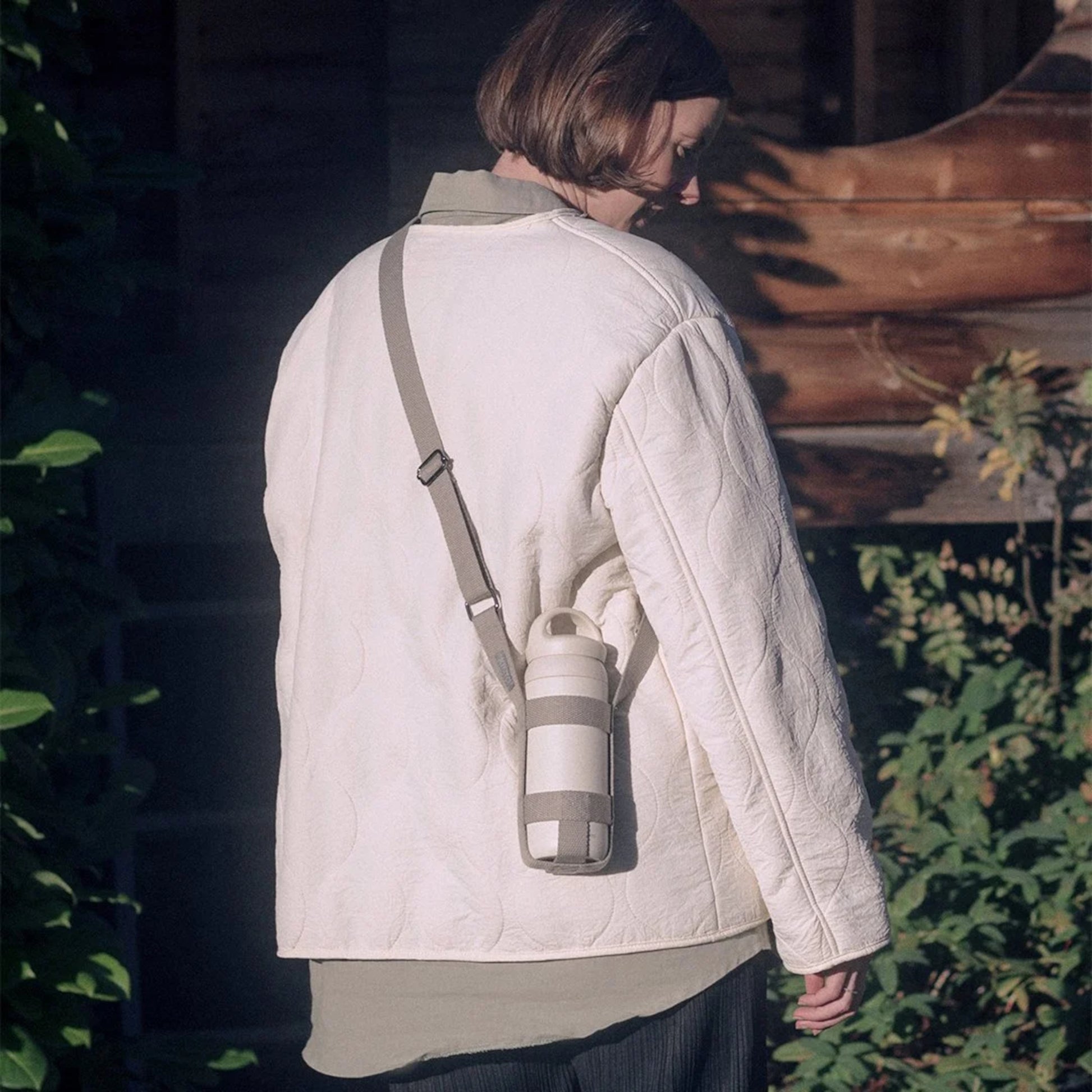 Woman carrying KINTO Tumbler strap medium in Beige holding day off tumbler