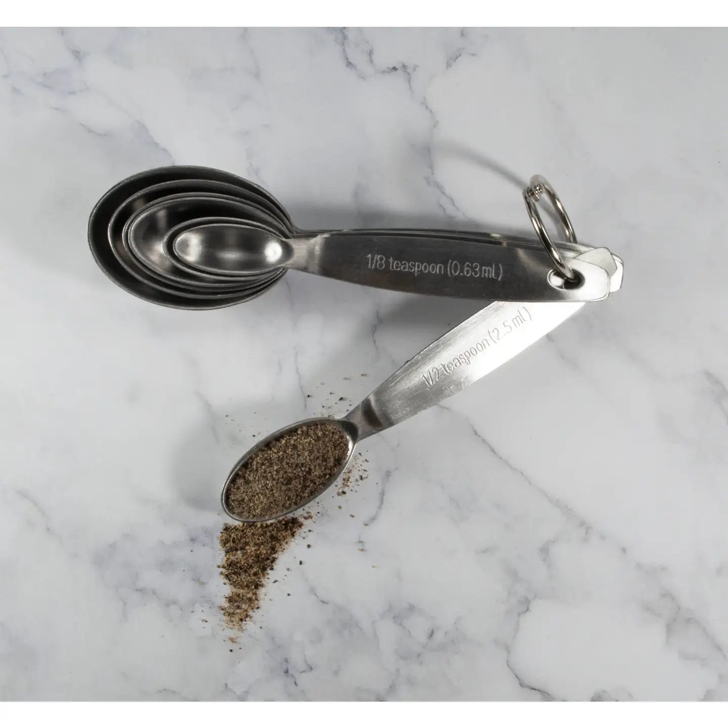 Set of metal measuring spoons with spices on a marble surface