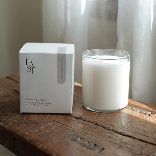 Candle and packaging on a wooden surface with a neutral background