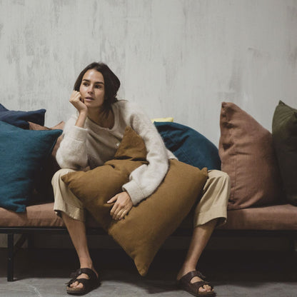 Woman sitting on a couch with Libeco Hudson Pillow Cover Collection