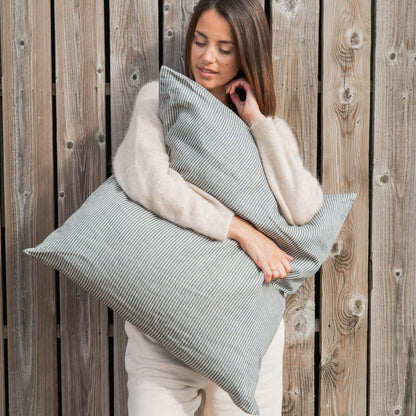 Woman holding Libeco Sailors Stripe Pillow against a wooden background