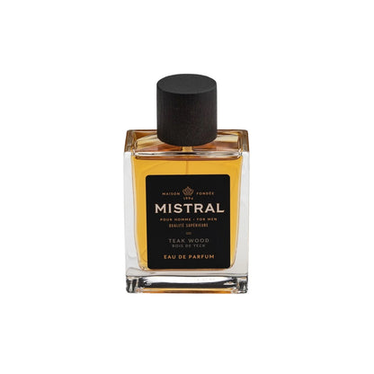 A square glass bottle of Mistral Eau de Parfum with a black cap. The label shows the fragrance name 'Teak Wood' and the bottle contains 100ml of the product.