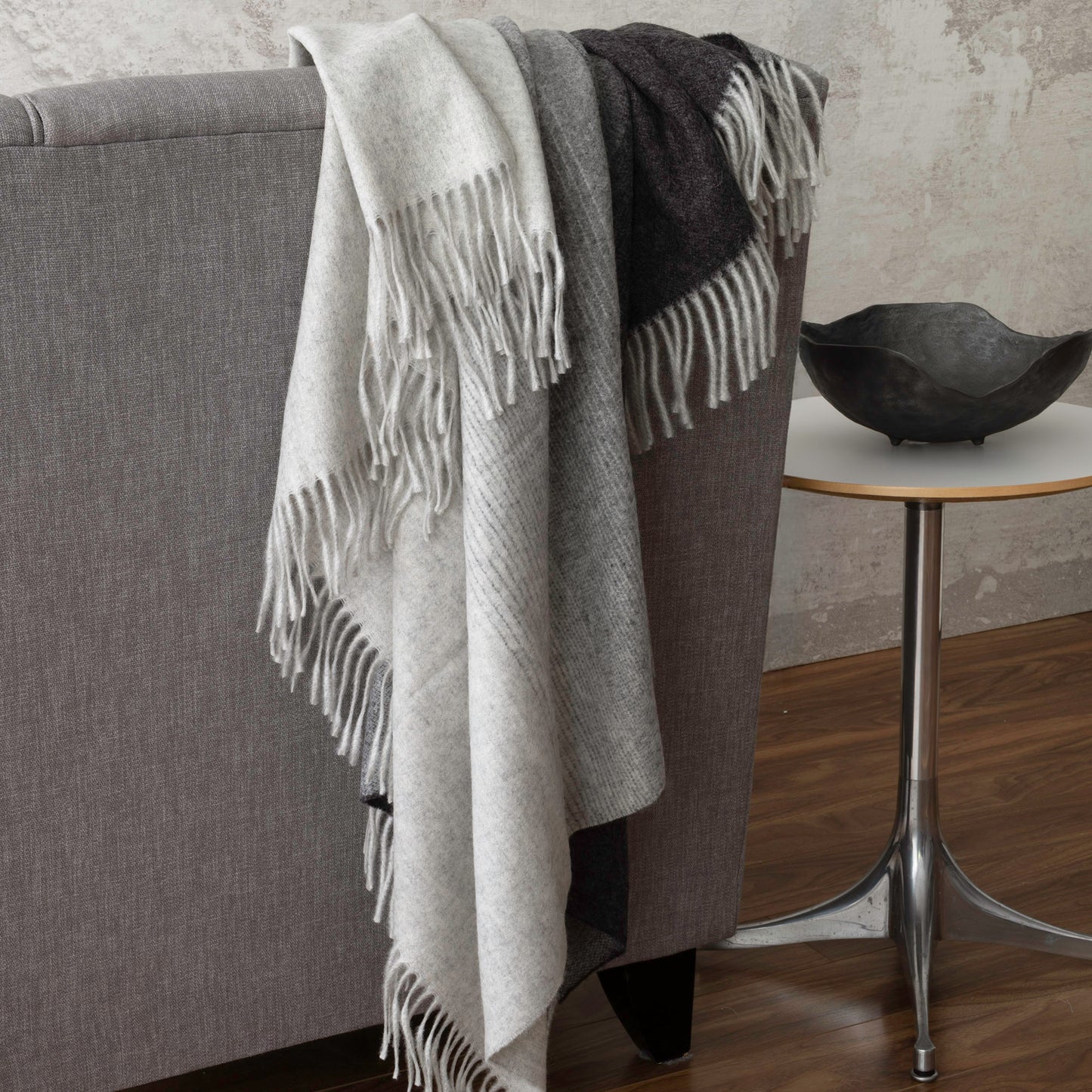 St Geneve Aria Throw Blanket in Charcoal, draped over sofa