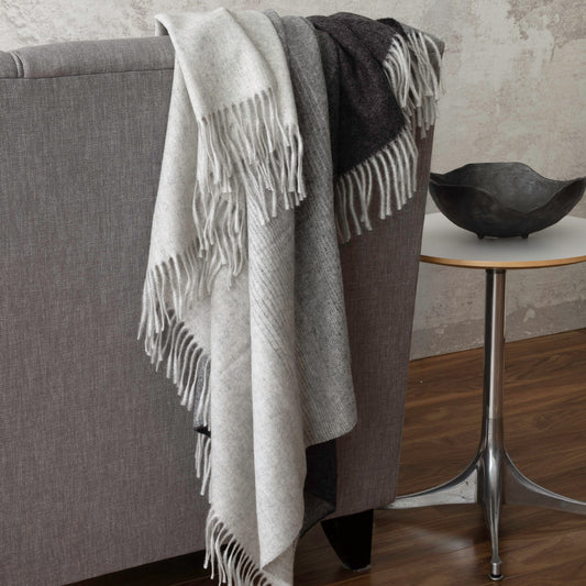 St Geneve Aria Throw Blanket in Charcoal, draped over sofa