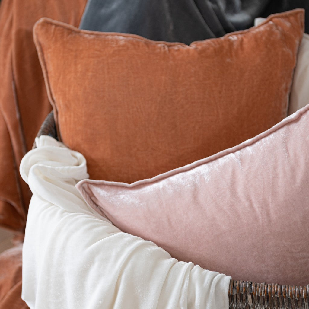 Close-up of two pillows, one orange and one pink, on a textured surface.