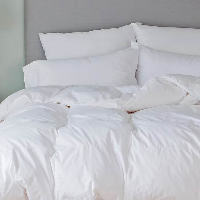 White bedding set on a bed with a gray headboard.