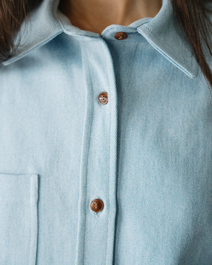 CLOSE UP COLLAR SHOT OF FEMALE MODEL WEARING LIGHT BLUE DENIM SHIRT