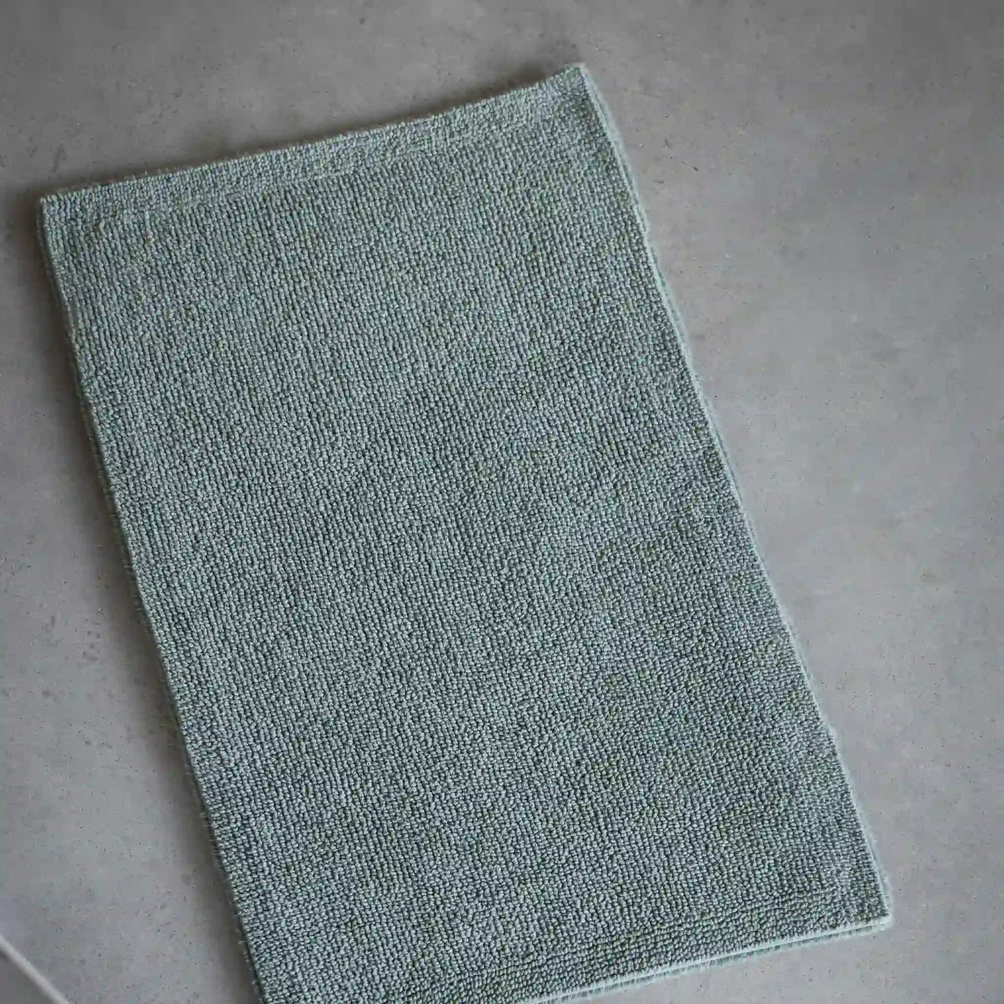 Green bath mat on a gray floor