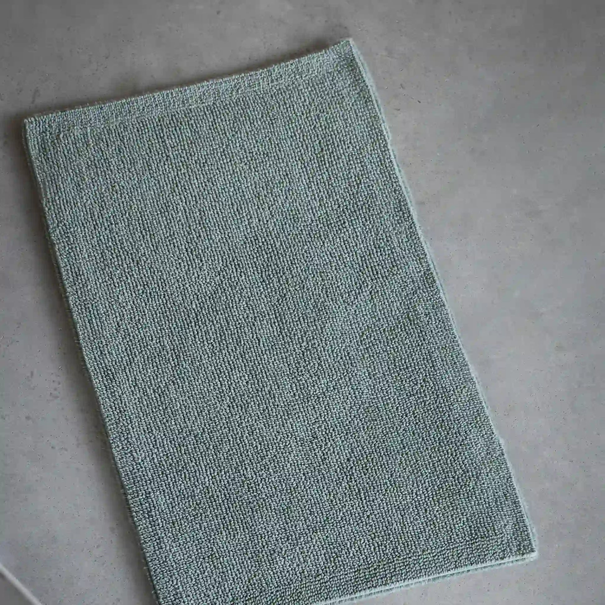 Green bath mat on a gray floor