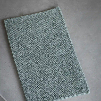 Green bath mat on a gray floor
