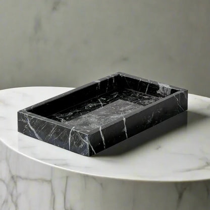 Black marble tray on a white marble pedestal against a gray background