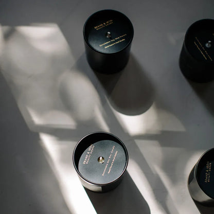 Black candles with gold text on a textured surface
