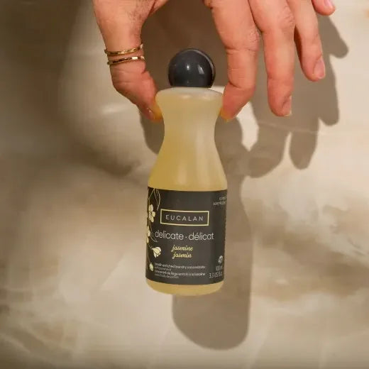 Bottle of Eucalan delicate jasmine soap held by a person on a neutral background