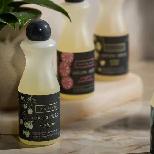Bottles of Eucalan laundry detergent on a surface with a blurred background