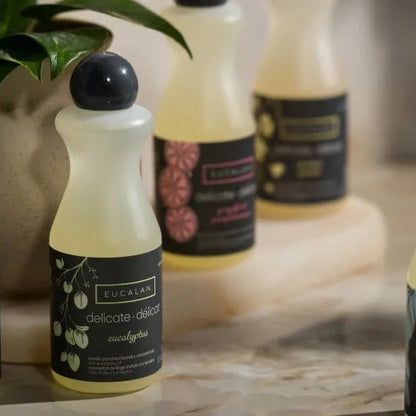 Bottles of Eucalan laundry detergent on a surface with a blurred background