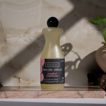 Eucalan delicate laundry soap bottle on a marble surface with a plant in the background