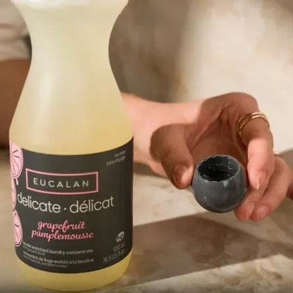 Eucalan delicate laundry detergent bottle with a person holding a black cap.