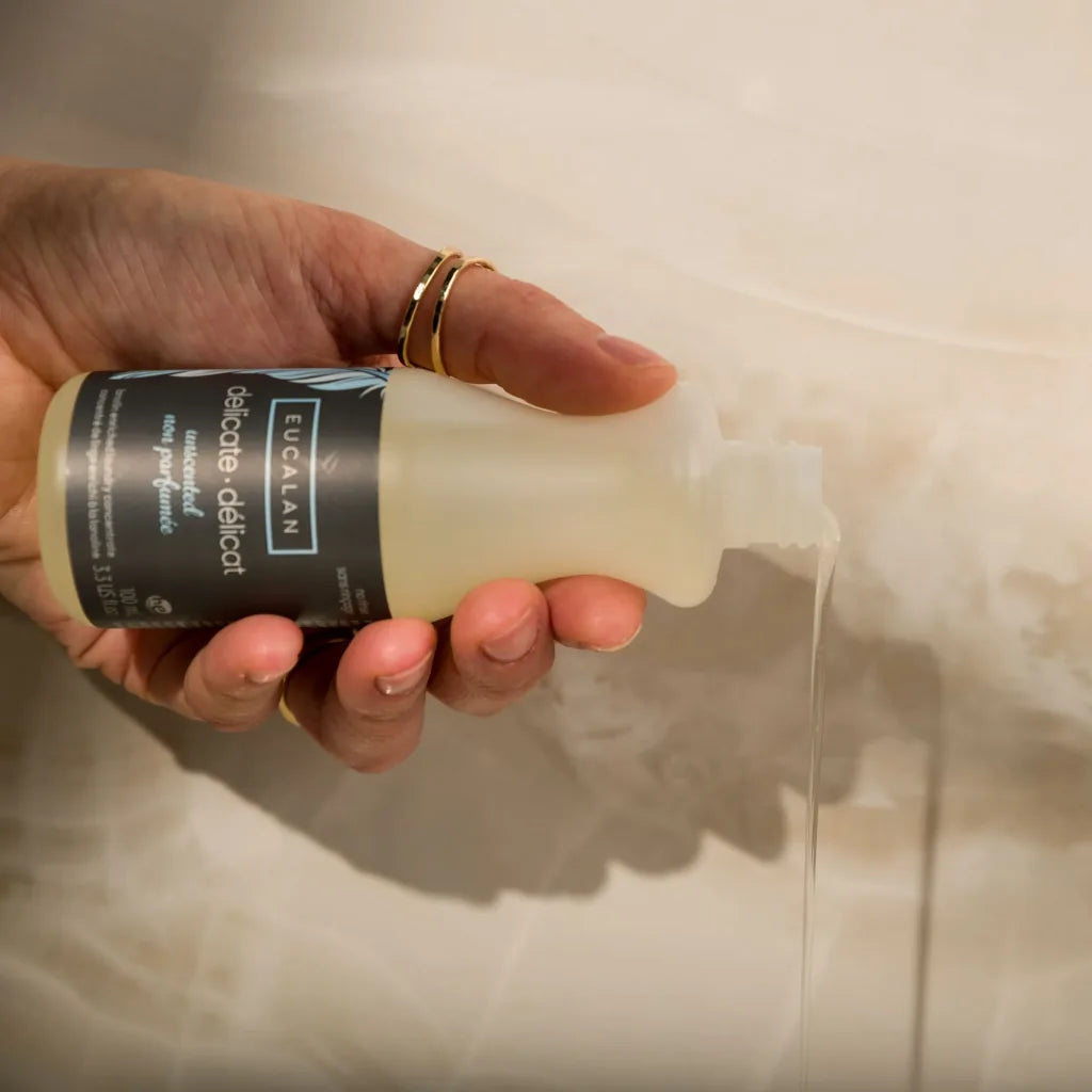 Hand holding a bottle of Eucalan laundry wash with a visible label.
