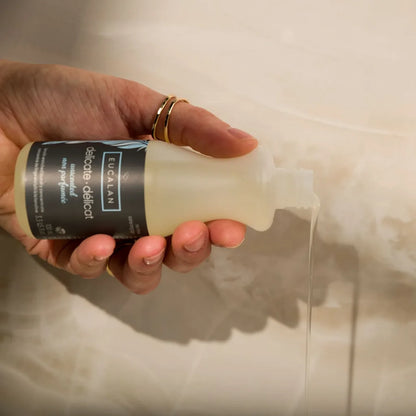 Hand holding a bottle of Eucalan laundry wash with a visible label.
