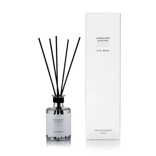 Diffuser with black sticks and white label next to its packaging on a white background