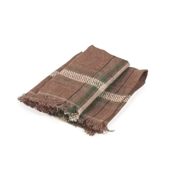 A folded brown plaid napkin with fringed edges, featuring beige herringbone patterns and green stripes, displayed on a clean white background.