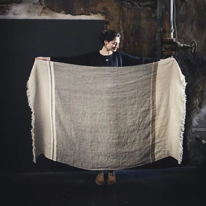 Person holding a large woven blanket with a dark background