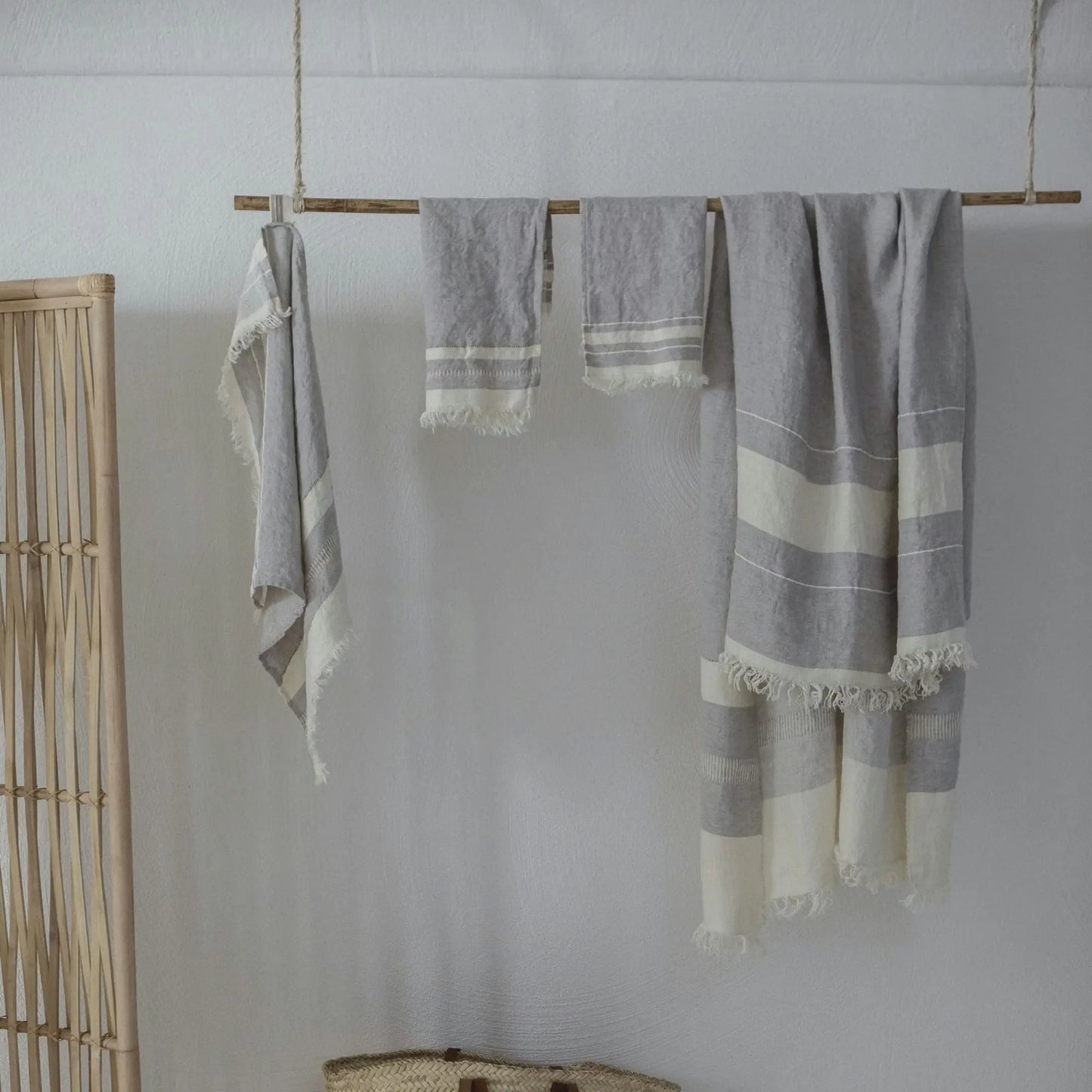 Gray and white striped towels hanging on a wooden rod against a white wall.