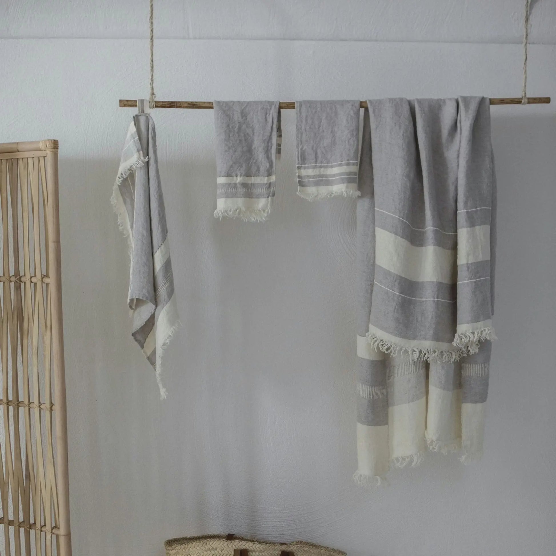 Gray and white striped towels hanging on a wooden rod against a white wall.
