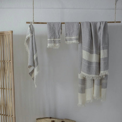 Gray and white striped towels hanging on a wooden rod against a white wall.