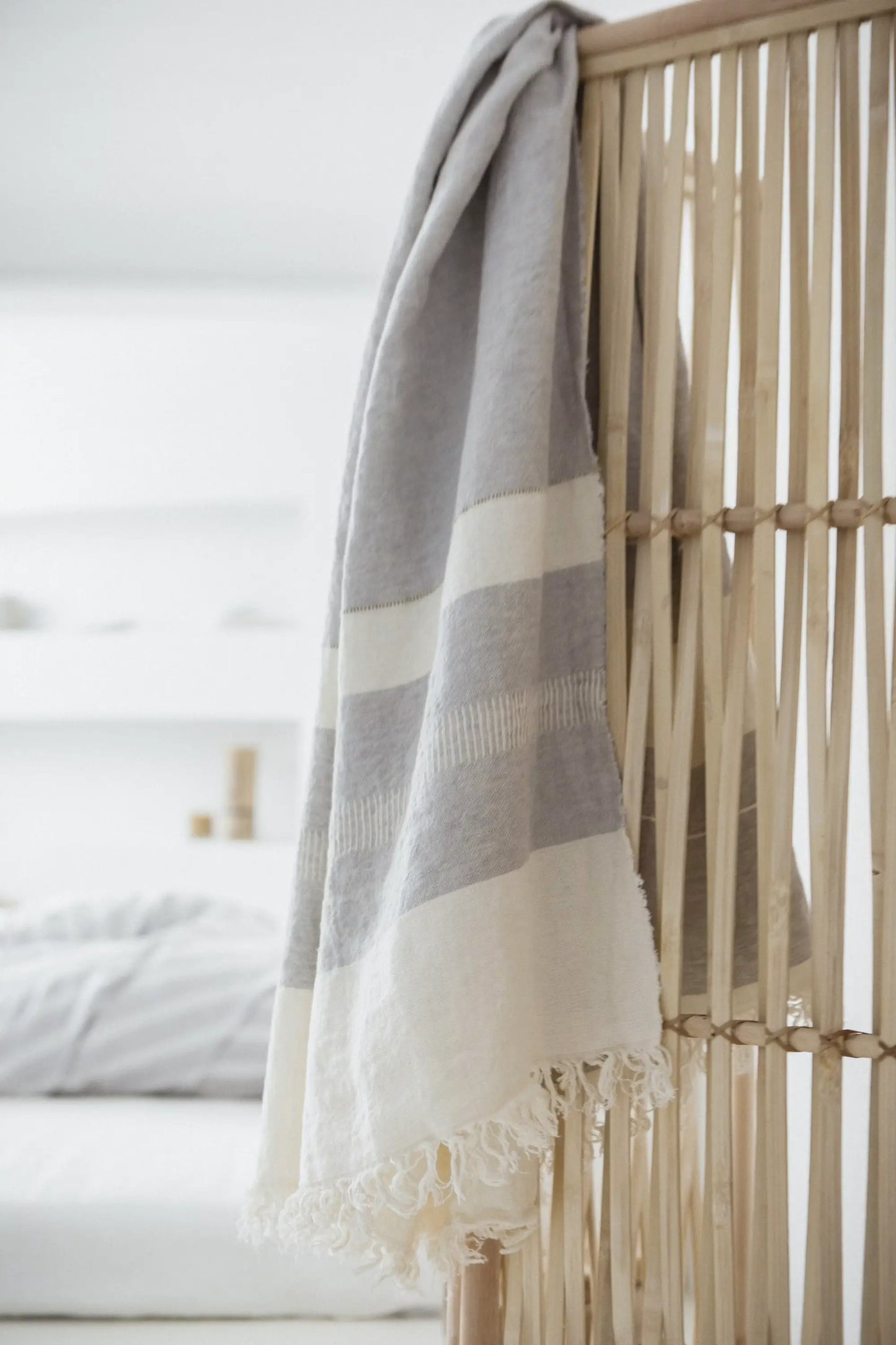 Gray and white striped blanket draped over a wooden room divider.