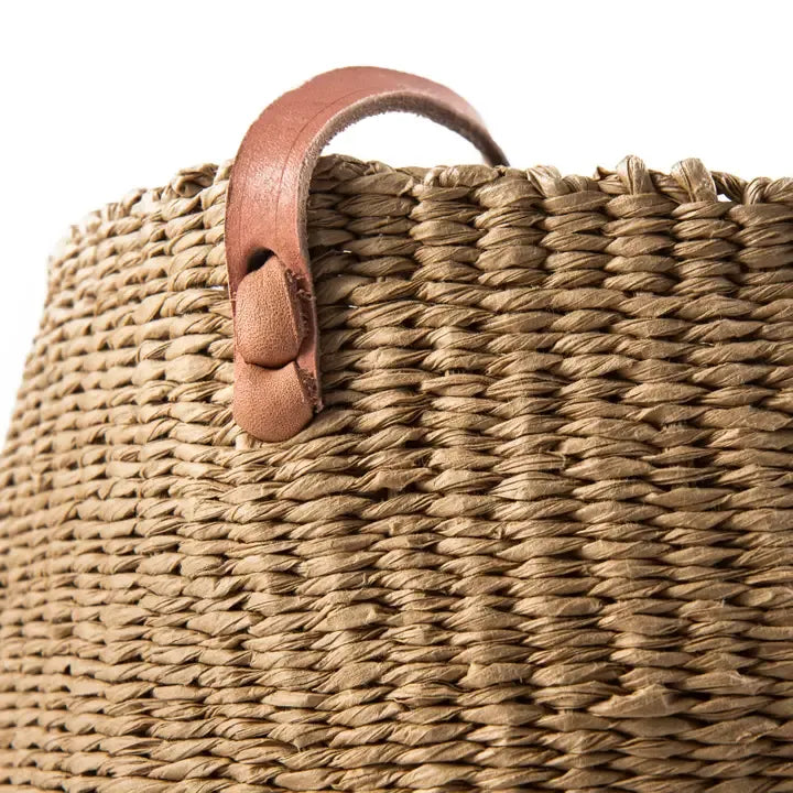 Woven basket with a leather handle on a white background
