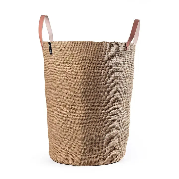 Beige woven laundry basket with leather handles on a white background