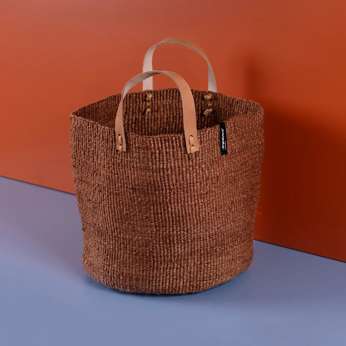 Woven basket with leather handles on a gradient background