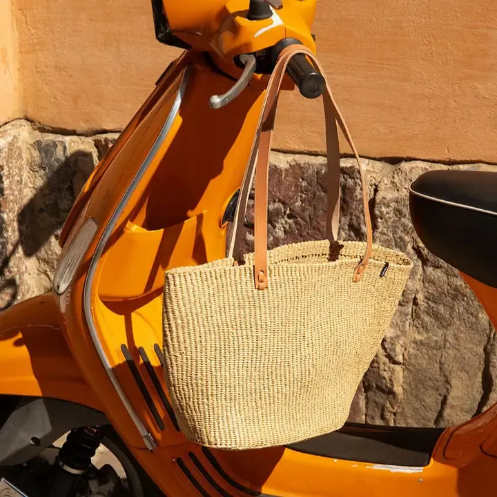 Woven bag on an orange scooter against a stone wall